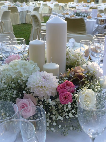 Charmante Tischdekoration zur Hochzeit mit Kerzen und Blumen Eine romantische Atmosphäre verströmt dieses edle Gesteck aus weißen Stumpen-Kerzen in RAL-Qualität und frischen Blumen. In den Abendstunden sorgt das Licht der Kerzen zusätzlich für eine stimmungsvolle Beleuchtung. Foto: Gütegemeinschaft Kerzen.